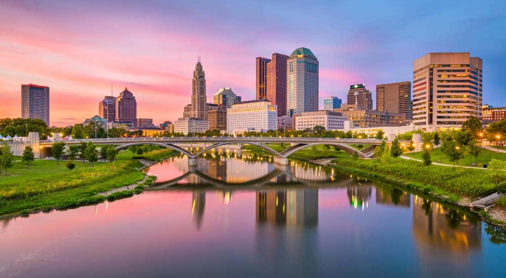 Tall buildings standing behind green grass and a body of water