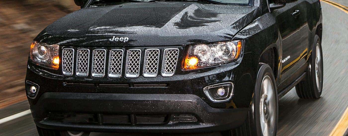 Closeup of the grille on a Black 2016 Used Jeep Compass driving in the rain