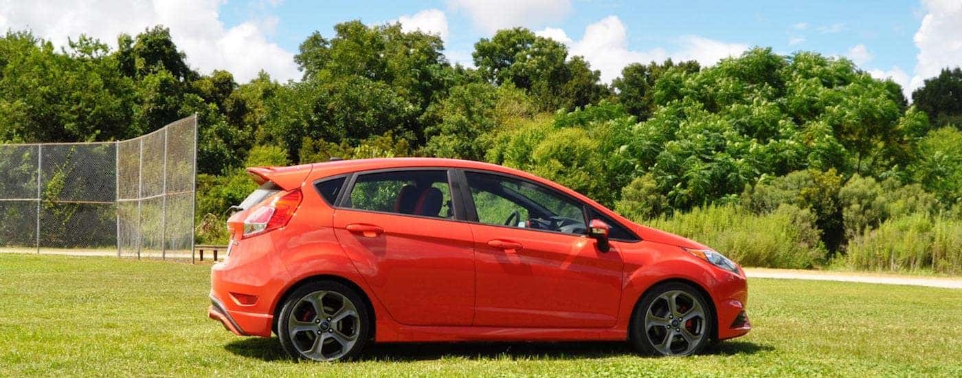 Red 2015 Used Ford Fiesta in front of a baseball field