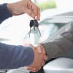 People shaking each other hands while holding car keys