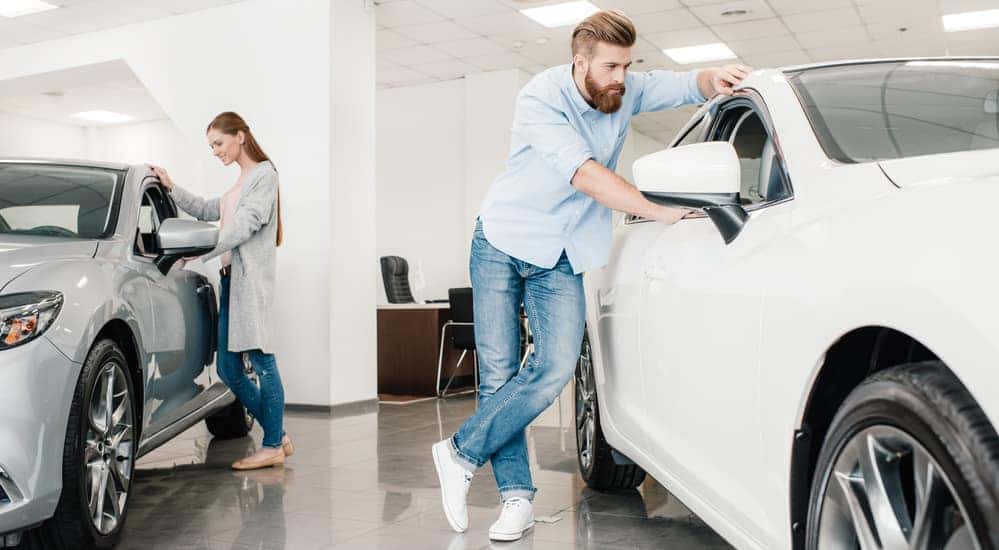 Man and woman looking at cars in showroom