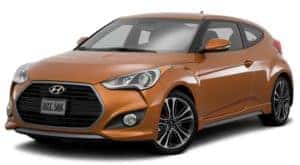 An orange 2015 used Hyundai Veloster is facing left.