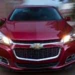 A red Chevy car driving fast down a road near a buy here pay here Louisville dealership
