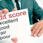 A closeup is shown of a credit score sheet being held by a man in a suit.