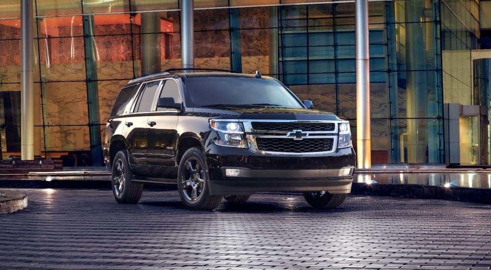 A black 2017 used Chevy Tahoe is parked in front of a glass building near Cincinnati, OH.