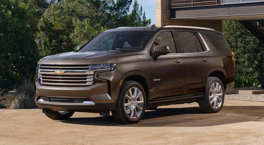 A grey 2021 Chevy Tahoe is parked in front of a modern home.