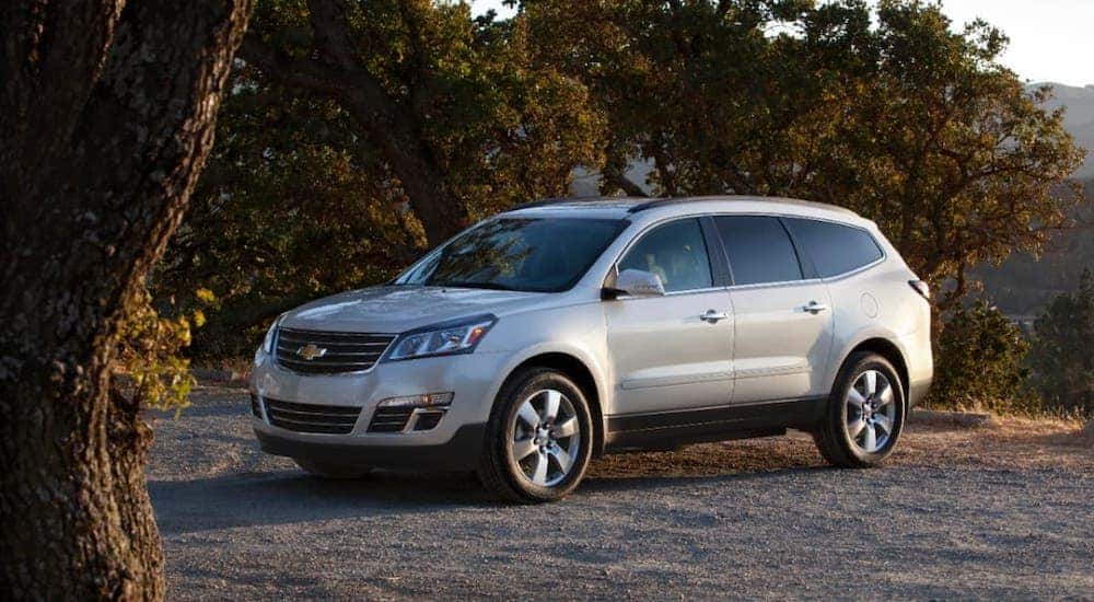 A silver 2013 Used Chevy Traverse is parked in front of trees near Cincinnati.