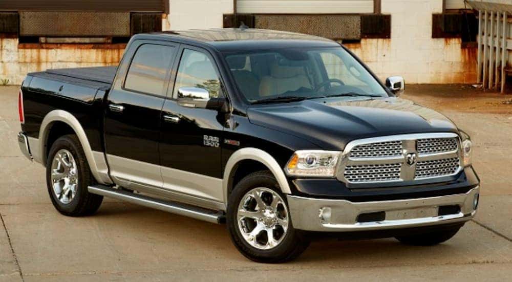 A black 2014 used Ram 1500 is parked in a loading bay.