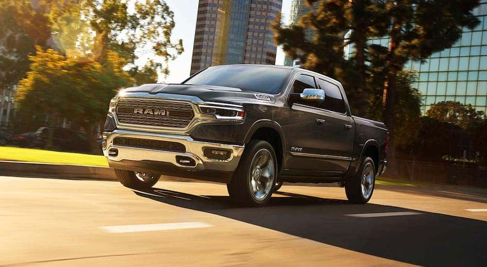 A grey 2019 used Ram 1500 is driving on a sunny city street in Cincinnati, OH.