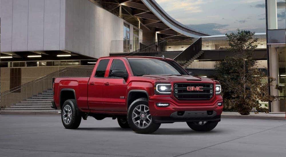 A red 2018 used GMC Sierra is parked in front of a modern building.