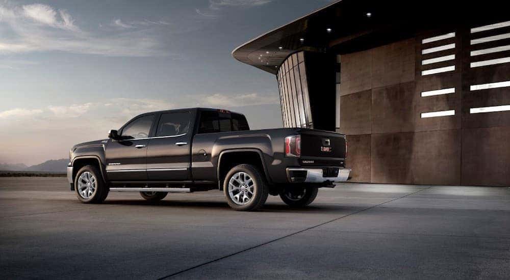 A black 2018 used GMC Sierra is shown from the rear parked at a modern building near Cincinnati, OH.