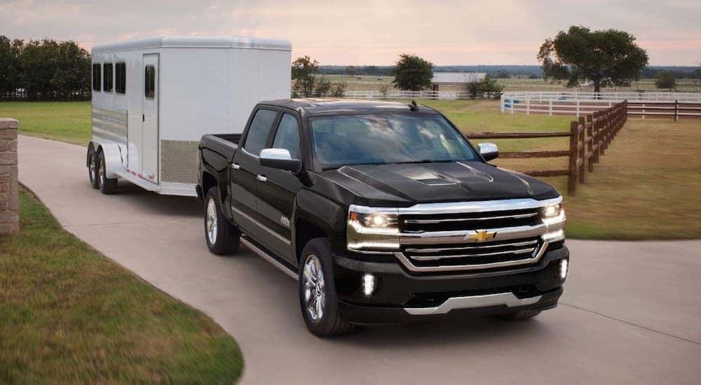 A black 2018 Chevy Silverado is towing an enclosed trailer out of a ranch.