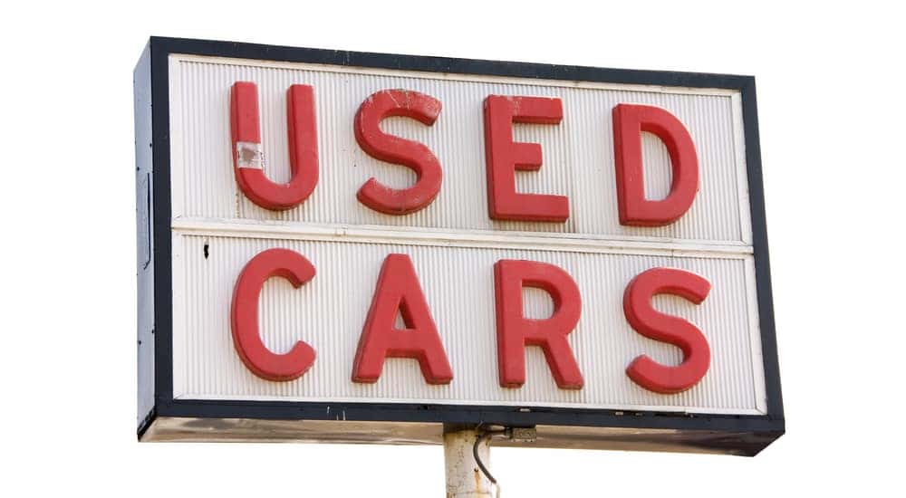 White sign with red words that read "Used Cars" against a white background