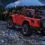 A red 2020 Jeep Wrangler Rubicon is shown from the back parked on rocks in the mountains.