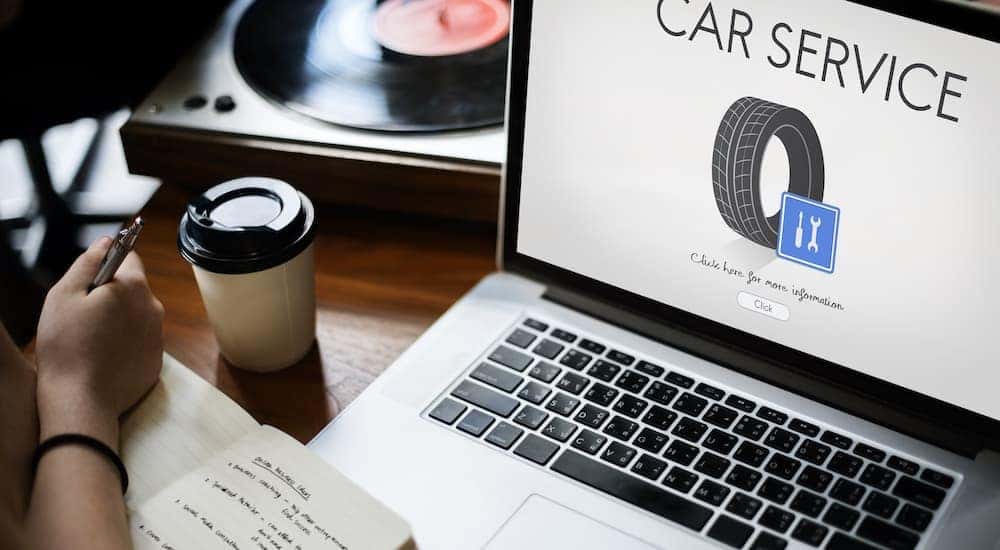 A person is shown writing down their car service records.