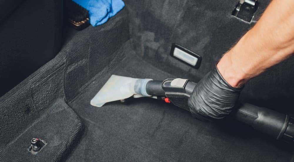 A person is shown vacuuming their car after searching 'used cars in Cincinnati.'