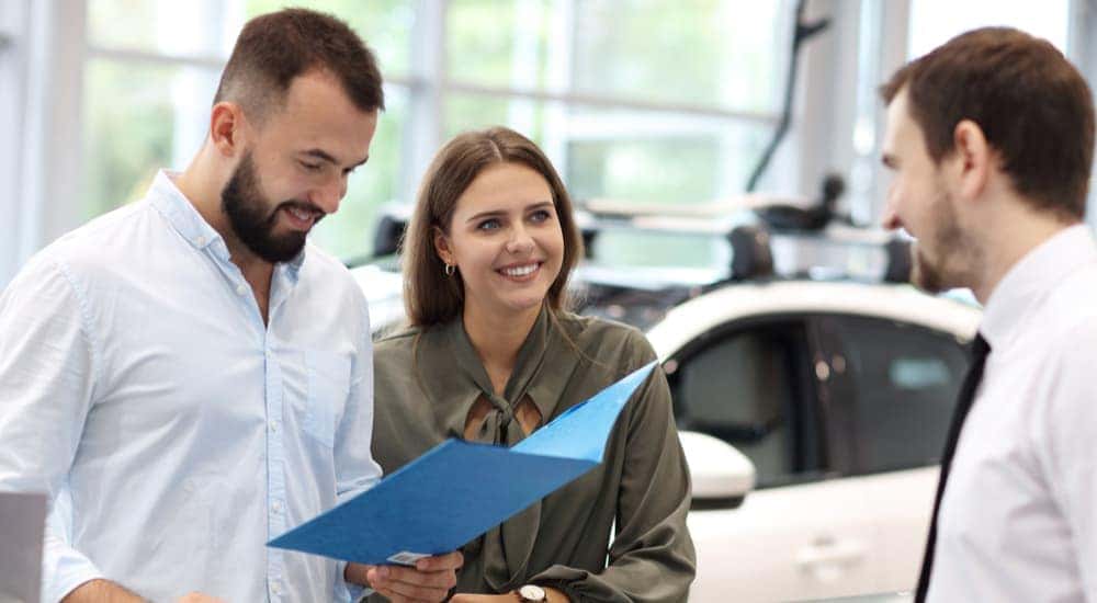 A couple is shown speaking to a salesman about how to 'sell my car.'