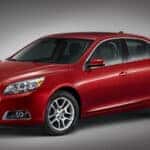 A red 2013 Chevy Malibu parked in a show room.