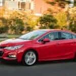 A red 2016 Chevy Cruze driving in a city.