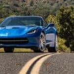 Two blue 2014 Chevy Corvette C7s parked on a highway.