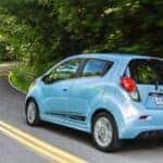 A blue 2015 Chevy Spark EV driving on a highway.