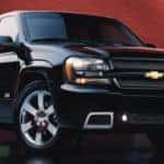 A black 2009 Chevy Trailblazer is parked in front of a red wall.