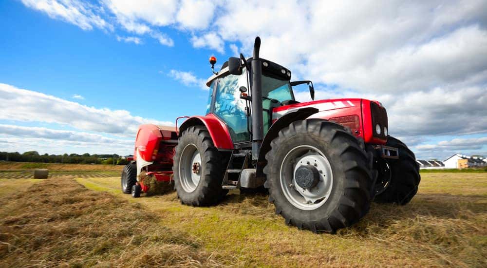 huge tractor collecting haystack in the field in a nice blue sunny day