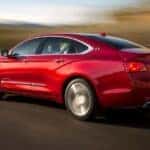 A red 2014 Chevy Impala driving on a highway.