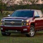 A red 2014 Chevy Silverado parked on grass.