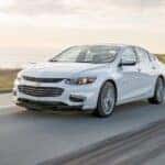 A white 2016 Chevy Malibu driving on a highway.