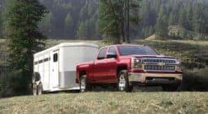 A red 2015 Chevy Silverado towing a trailer.