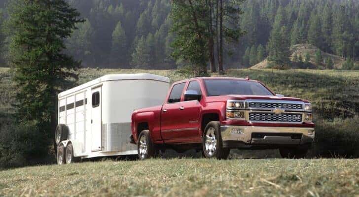 A red 2015 Chevy Silverado towing a trailer.