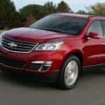 A red 2014 Chevy Traverse driving on a highway.
