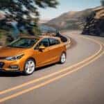 An orange 2018 Chevy Cruze driving on a highway.