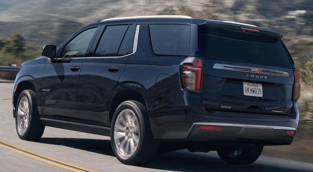 A black 2021 Chevy Tahoe is shown from the rear driving on an open road.