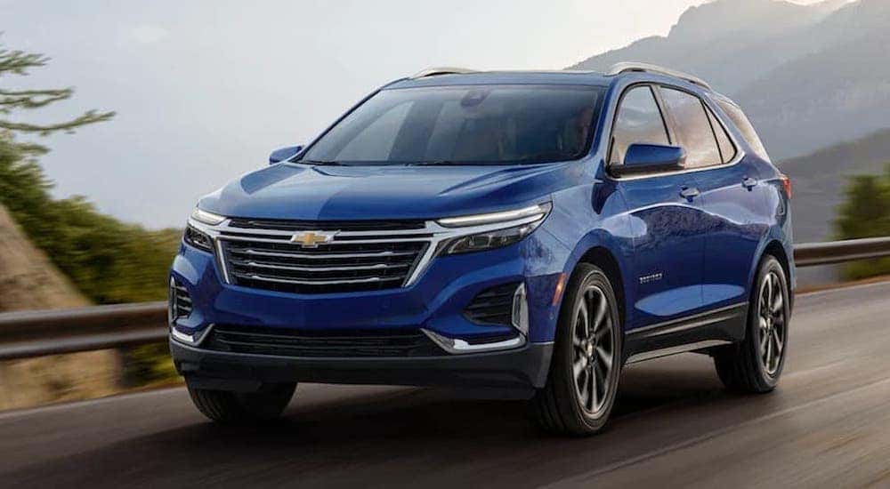 A blue 2022 Chevy Equinox is shown from the front driving on an open road.