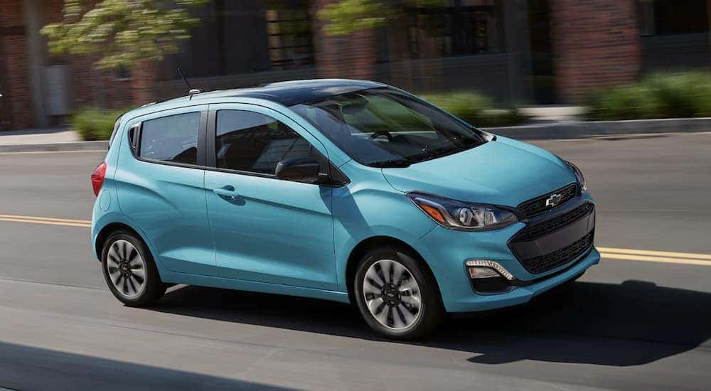 A turquoise 2022 Chevy Spark is shown from the side driving on an open road. 
