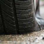 A flat tire is shown in closeup on pavement.