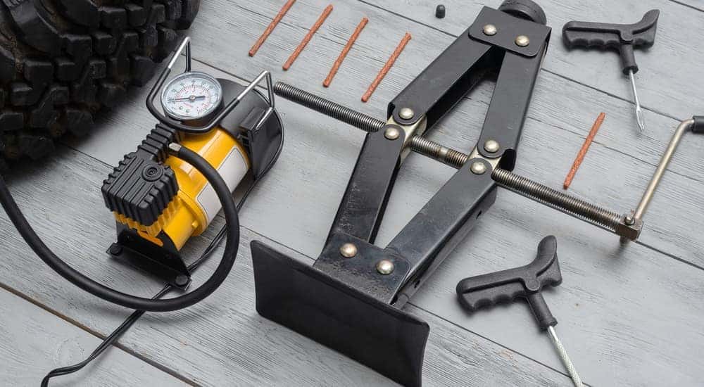 A jack, air compressor, and other tools for fixing a flat are shown on the floor at an Indy Chevy dealer.