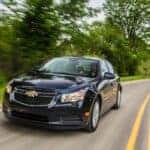 Black 2014 Chevy Cruze driving down a road.