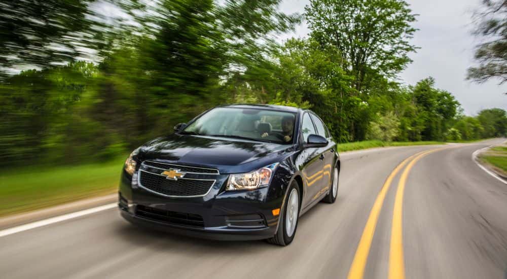 Black 2014 Chevy Cruze driving down a road.