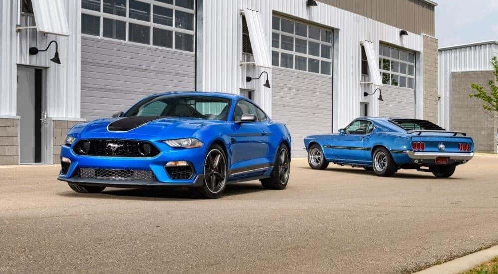 Blue 2021 Ford Mustang Mach-E parked beside a blue 1969 Ford Mustang.