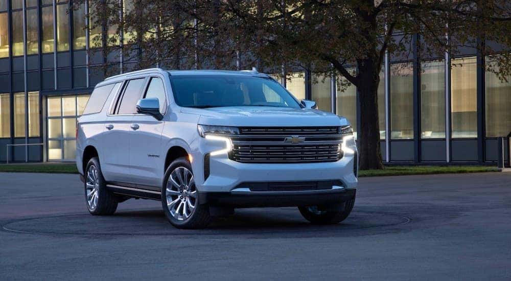 A white 2021 Chevy Suburban is parked in front of Cincinnati office building at dusk.