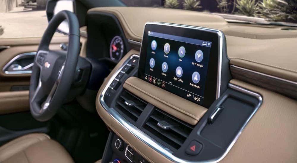 A closeup is shown of the infotainment and two-tone interior of a 2021 Chevy Suburban, showcasing the Chevy Tahoe and Suburban Technology.