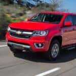 Red 2015 Chevy Colorado driving down a road.