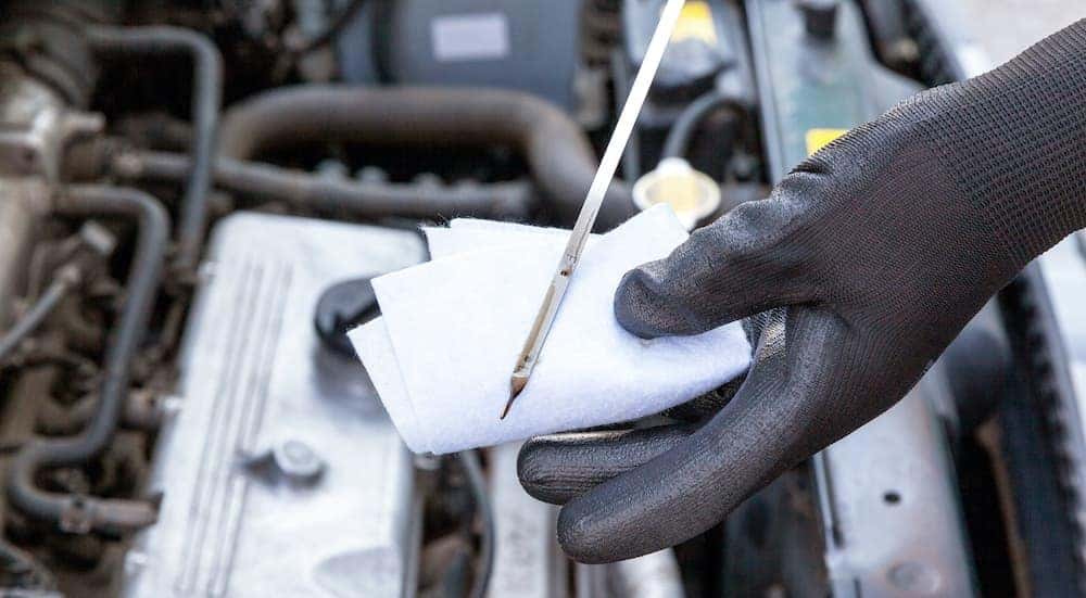 A gloved mechanic is preforming an oil change in Cincinnati.