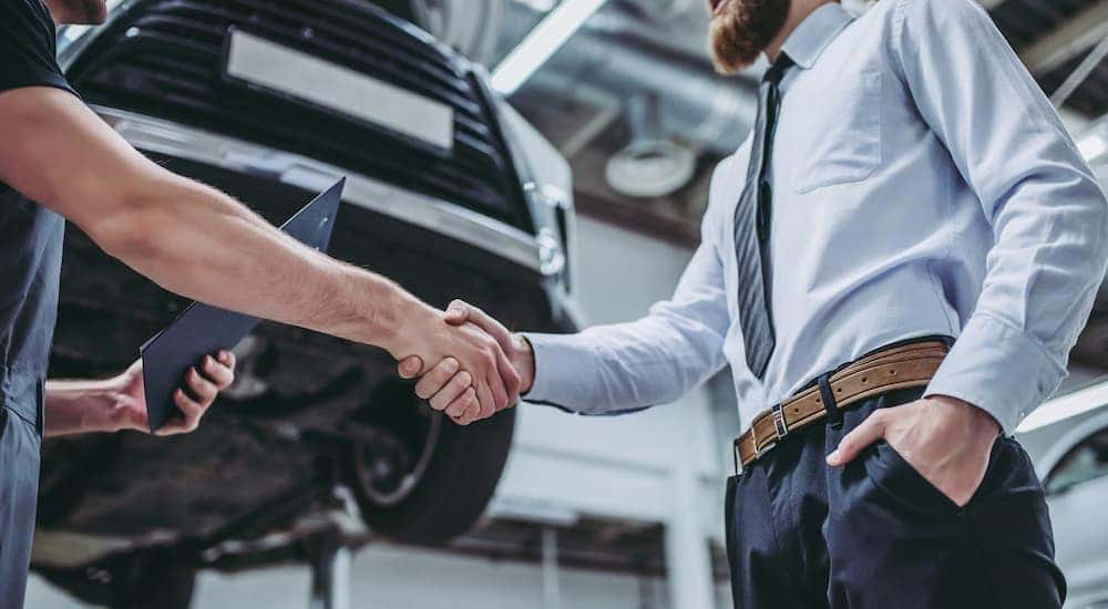 A man is shaking a mechanic's hand after asking about Cincinnati used car dealers.