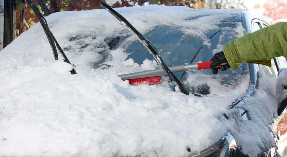A person is cleaning snow off the windshield.