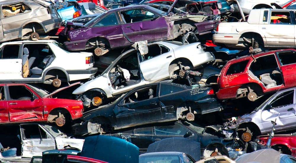 A junk yard is shown with cars piled high.