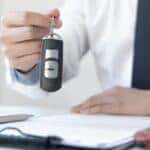 Someone holding a key fob over paperwork.